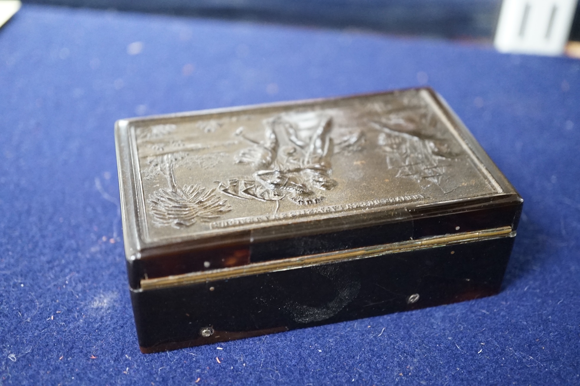 A 19th century Swiss small cylinder tortoiseshell musical snuff box, the hinged lid decorated with a scene of General Lafayette landing in America, with 6.5cm. cylinder, inscribed 'Arrivee du Gen Lafayette en Amerique',